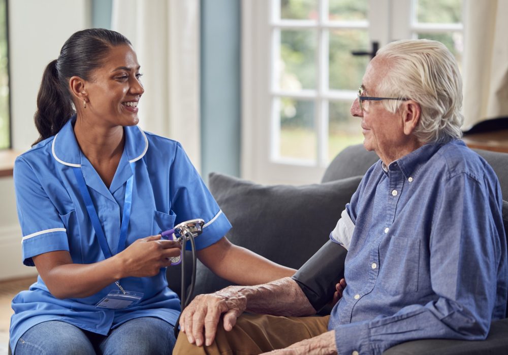 senior-man-at-home-in-lounge-having-blood-pressure-taken-by-female-care-worker-in-uniform.jpg